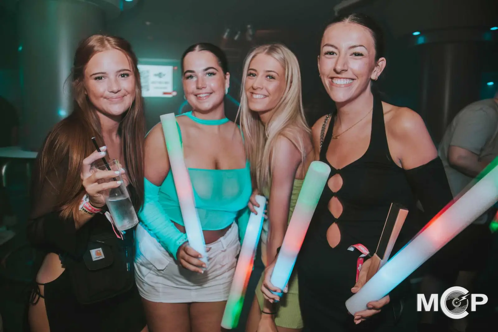 Friends holding glow sticks inside an MCP nightclub